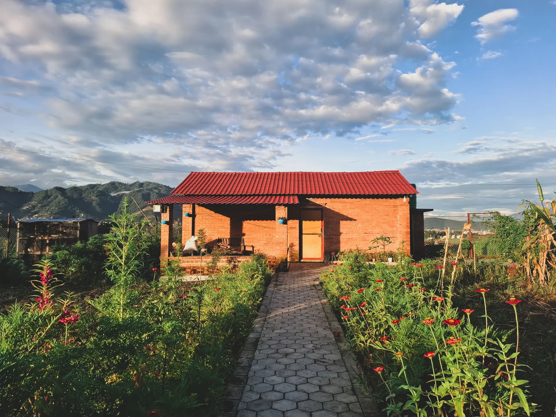 Small brick cottage with a red roof at the end of a garden path