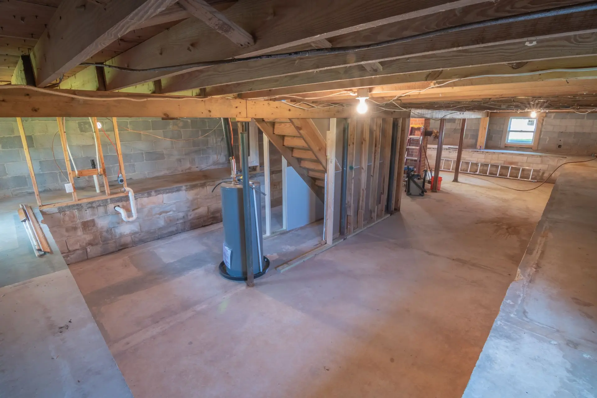 Lower floor stripped to open joists, framing and a water heater
