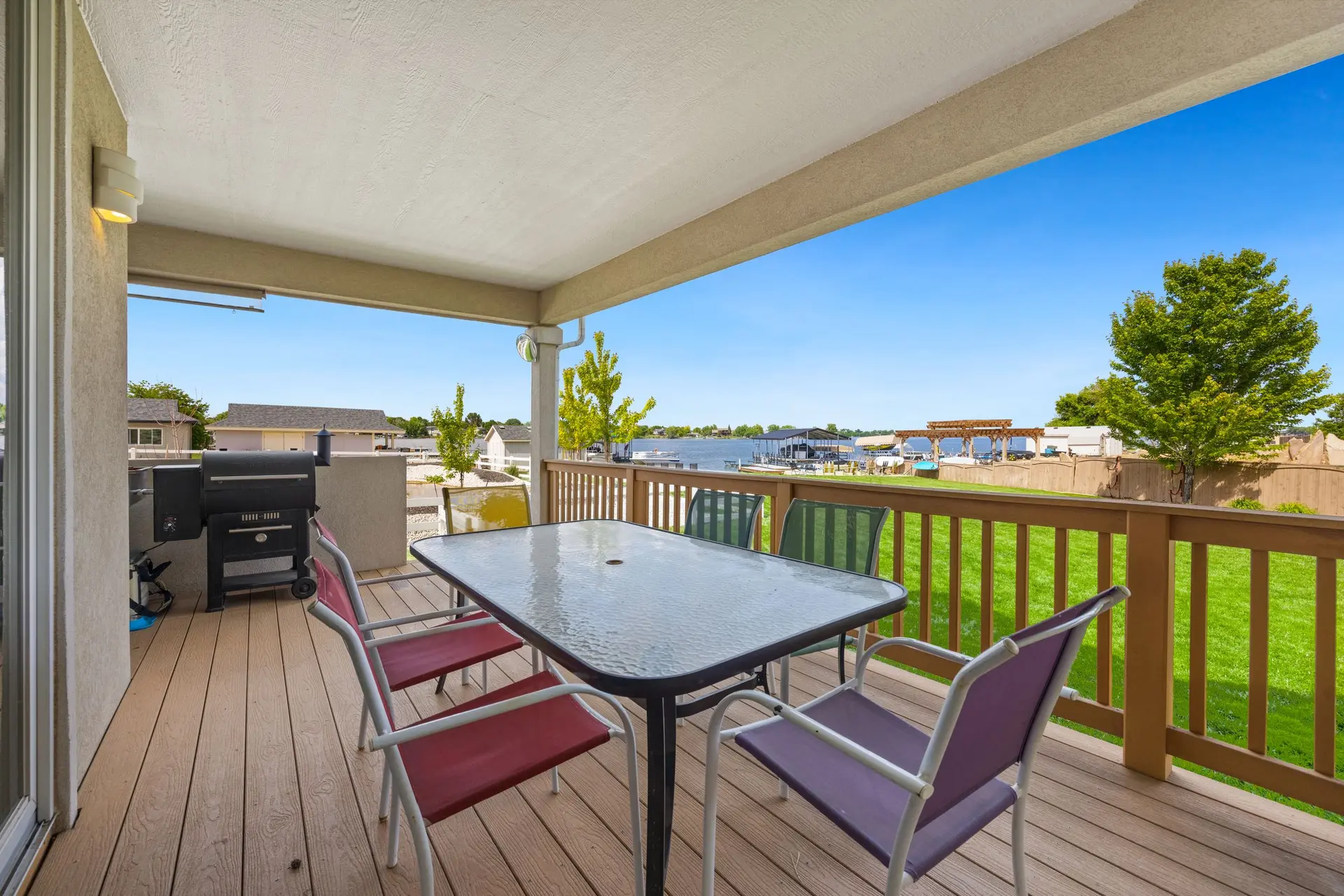 Covered wood deck with a glass table, chairs and a grill