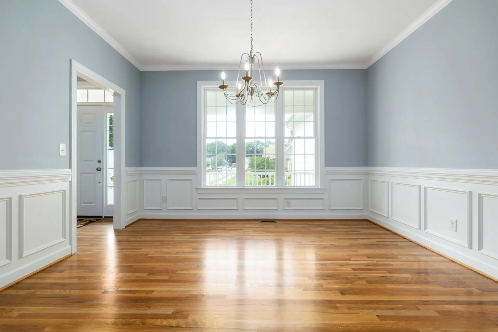 Empty dining room with a polished hardwood floor and white wainscoting