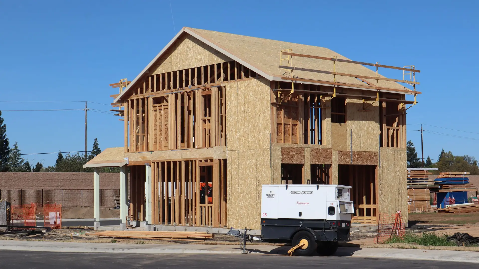Two-story house framed and sheathed with a generator parked in front