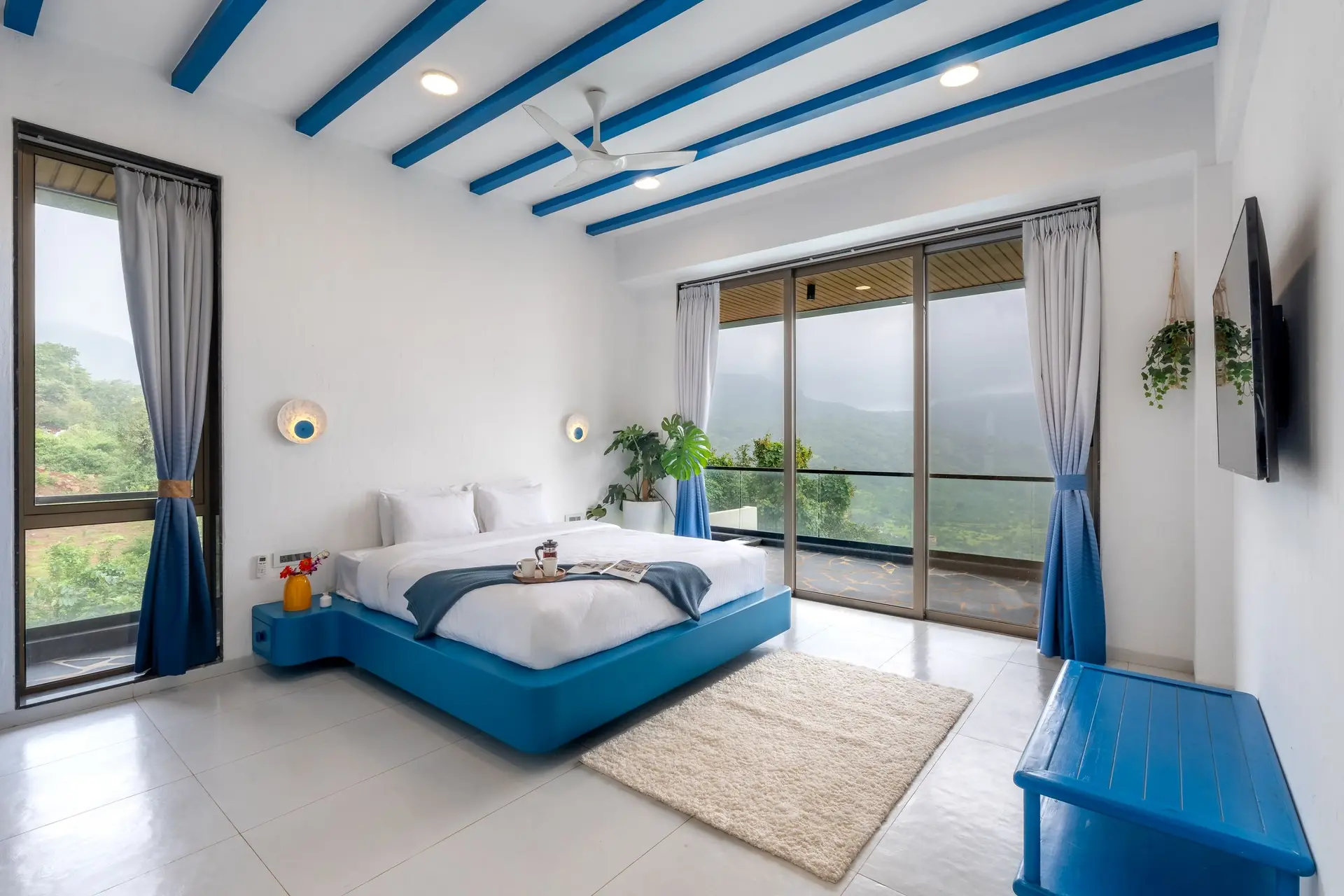 Bedroom with blue painted ceiling beams and a wall of windows