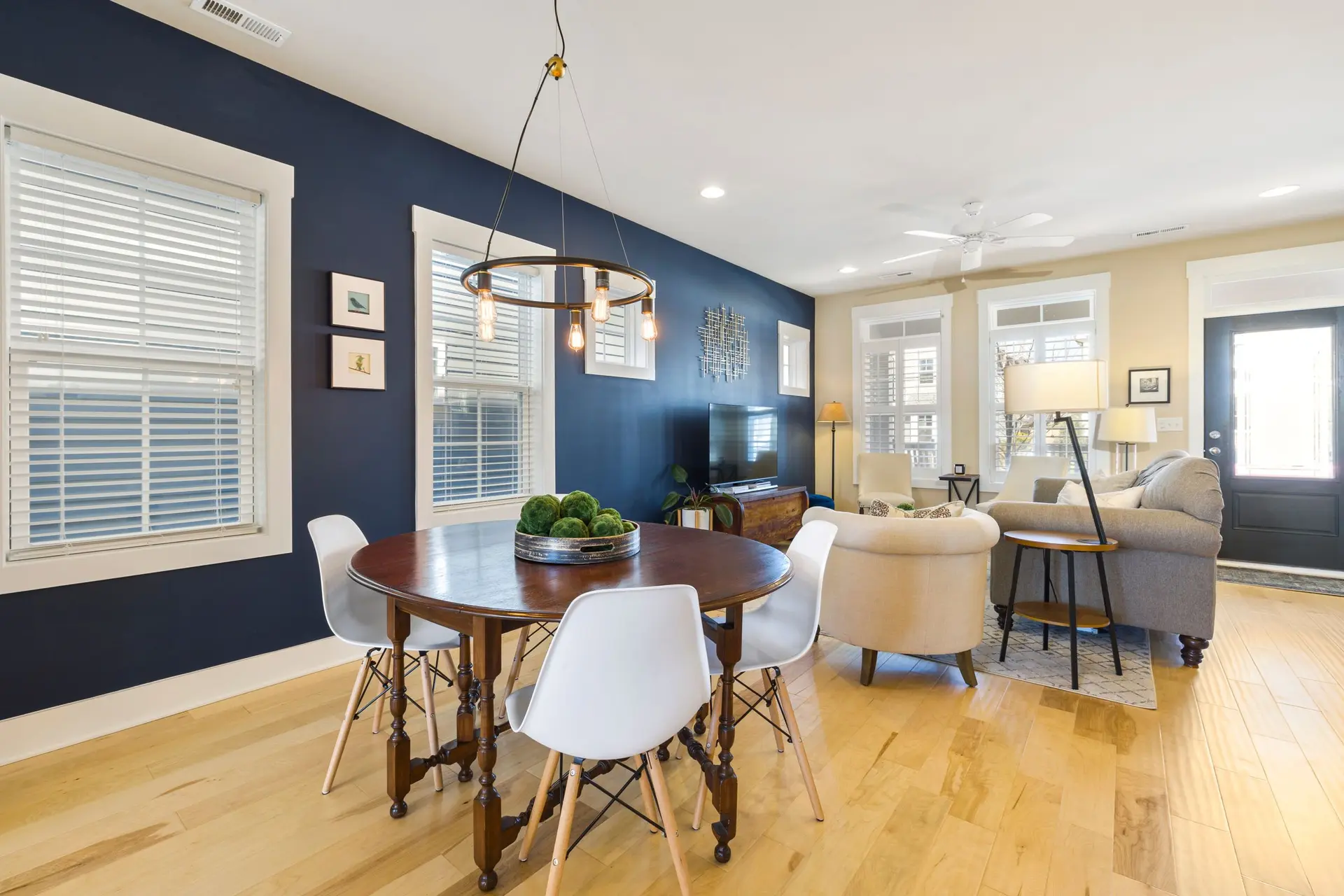 Open dining and living room with a navy accent wall and light oak floors